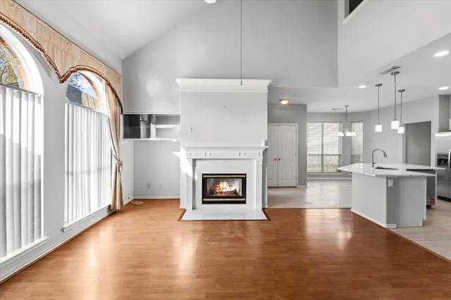 an empty room with wooden floor fireplace and windows