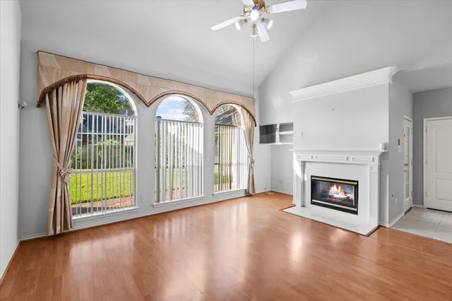 a view of an empty room with wooden floor fireplace and a window