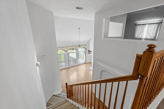 a view of a hallway with wooden floor and stairs