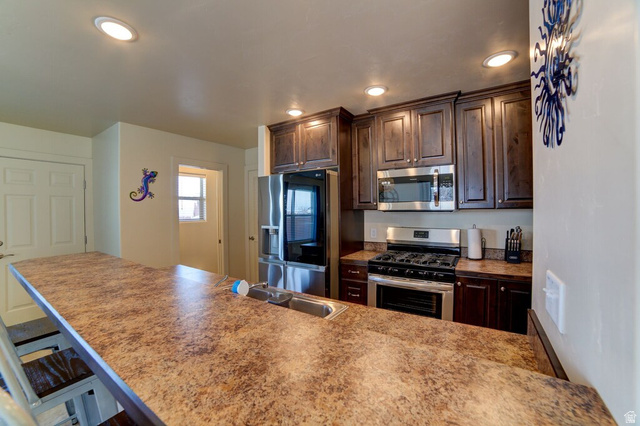 3853 South Red Valley Circle, Unit 22A1 Moab, UT 84532 - Photo 4 of 28 Kitchen with stainless steel appliances, dark wood finish cabinets, a breakfast bar area, and recessed lighting