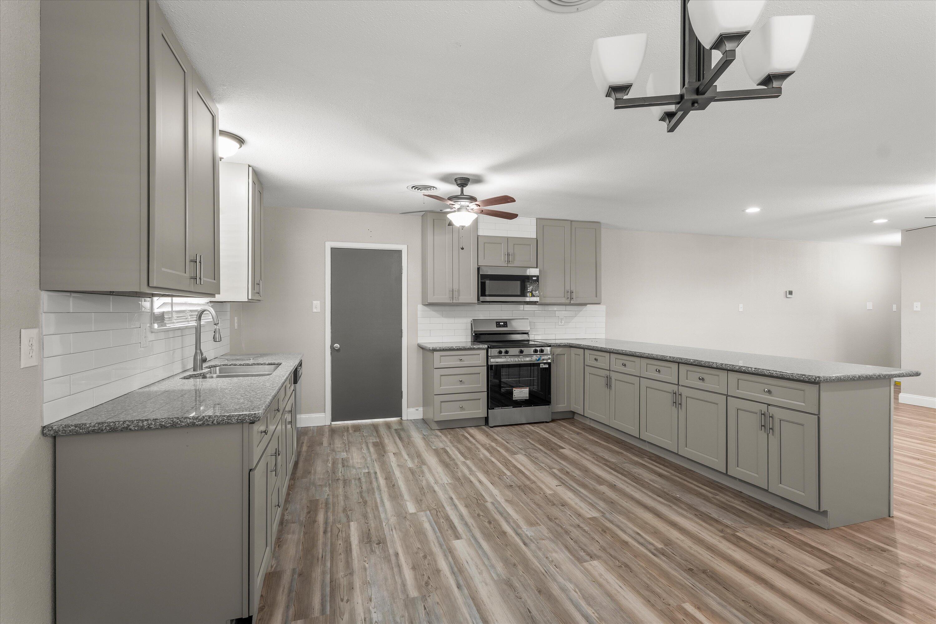3809 49th Street Lubbock, TX 79413 - Photo 7 of 24 a kitchen with kitchen island granite countertop a sink cabinets and stainless steel appliances