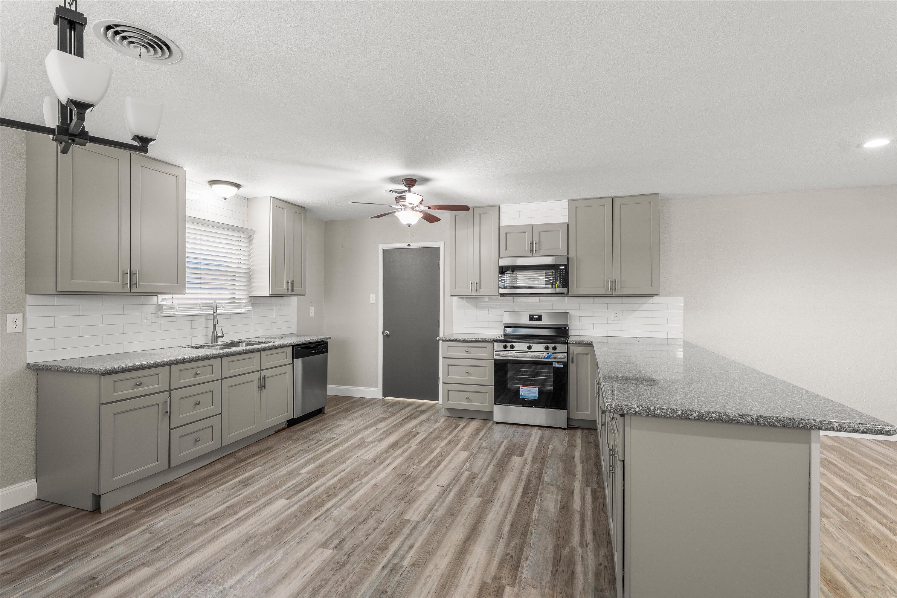 3809 49th Street Lubbock, TX 79413 - Photo 8 of 24 a large kitchen with kitchen island a sink stainless steel appliances and cabinets
