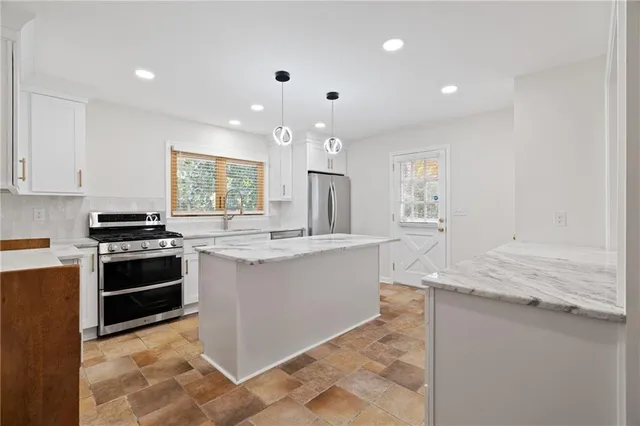 a kitchen with stainless steel appliances granite countertop a stove a sink and a refrigerator