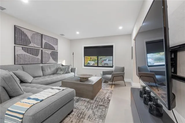 a living room with furniture a flat screen tv and a large window