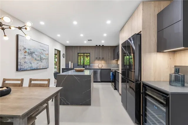 a kitchen with stainless steel appliances a table chairs in it and wooden floors