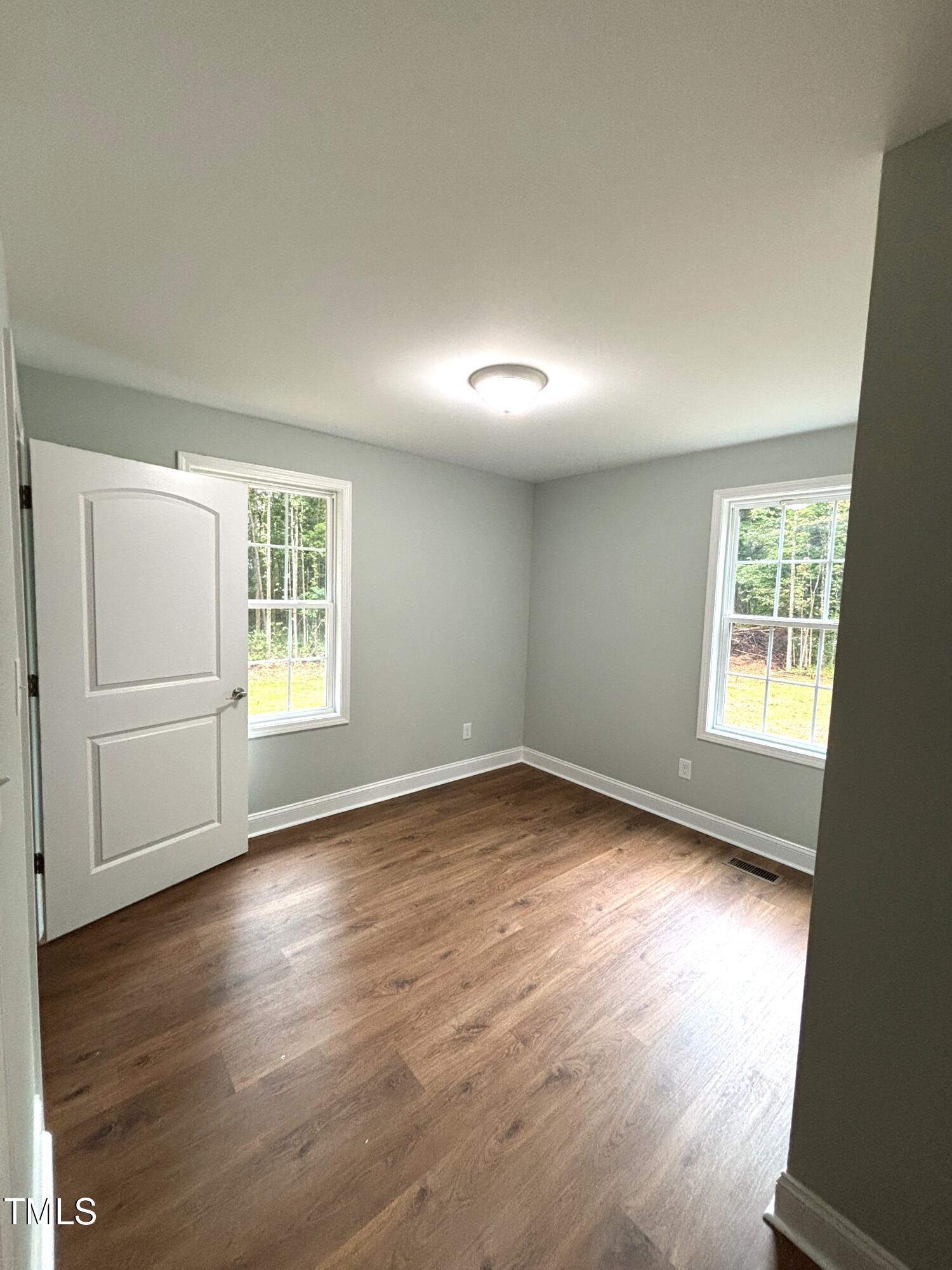 2665 Bodie Currin Road Oxford, NC 27565 - Photo 23 of 26 an empty room with wooden floor and windows