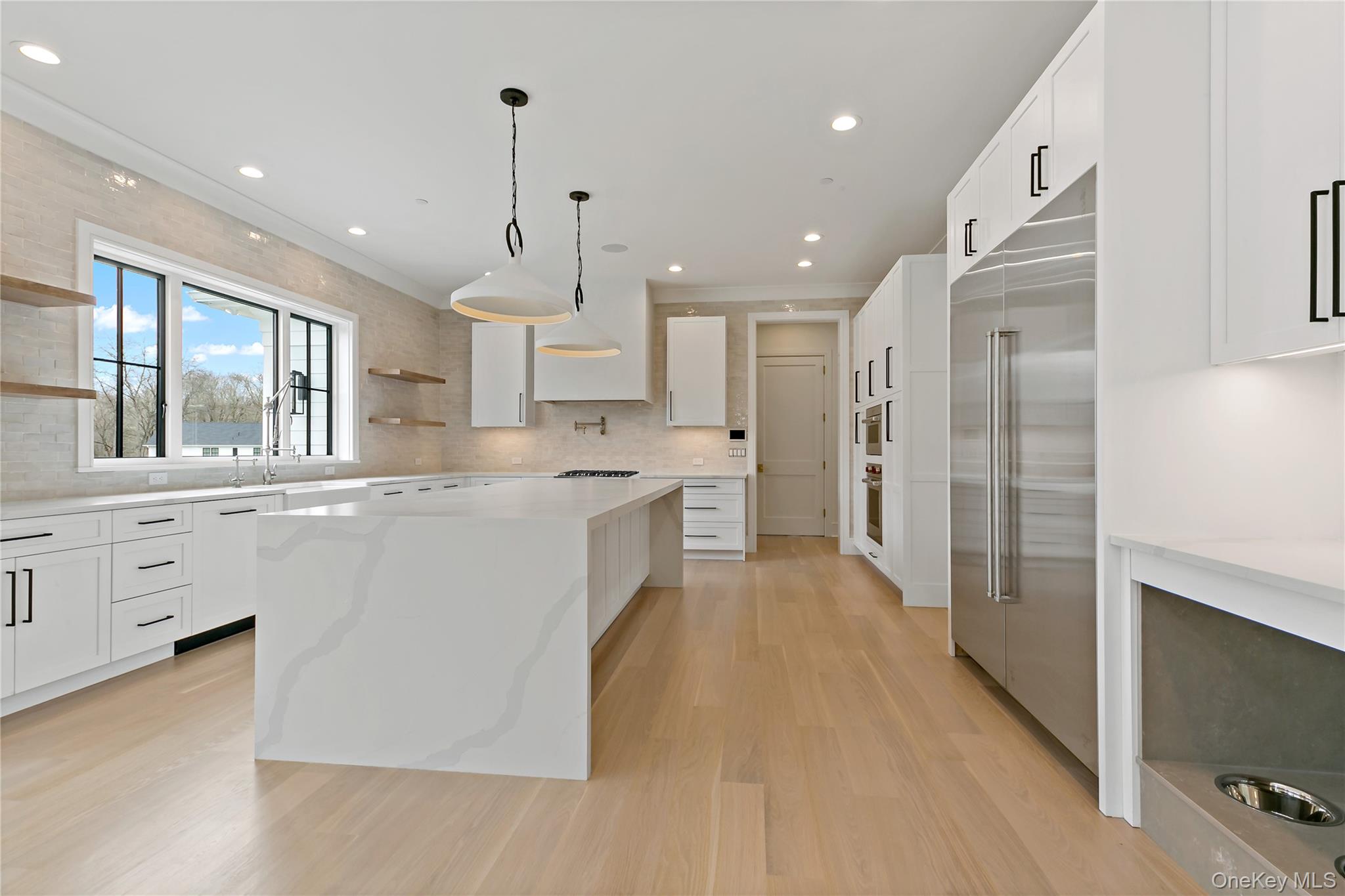 115 Old Roaring Brook Road Mount Kisco, NY 10549 - Photo 12 of 25 a large kitchen with stainless steel appliances kitchen island a large counter top and a refrigerator