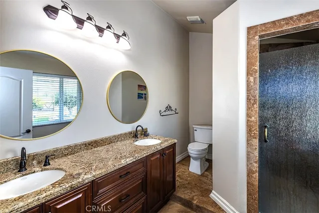 a bathroom with a granite countertop toilet a sink and a mirror