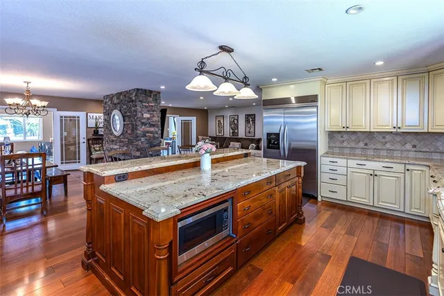 a kitchen with stainless steel appliances granite countertop a kitchen island a stove a sink a dining table and chairs
