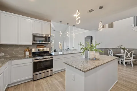 a kitchen with granite countertop a stove cabinets and wooden floor