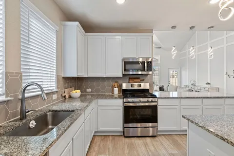 a kitchen with granite countertop a sink a counter space appliances and cabinets