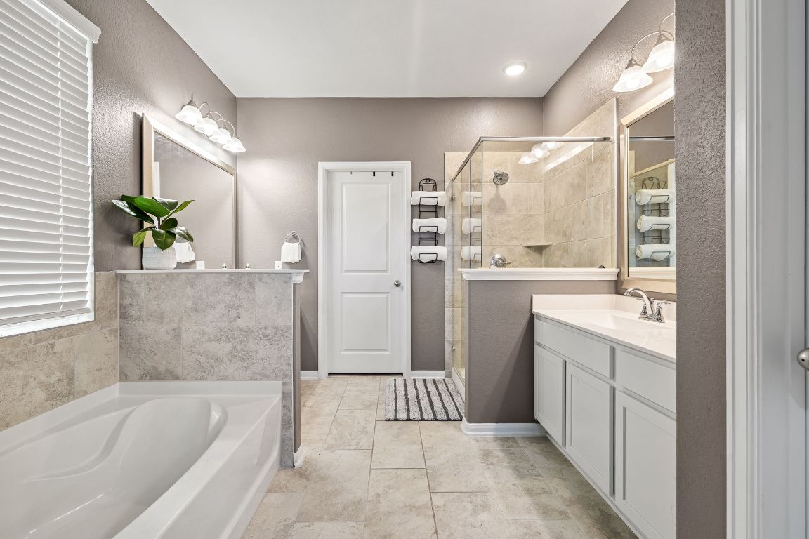 408 Ravello Street Liberty Hill, TX 78642 - Photo 20 of 40 a bathroom with a bathtub a sink a large mirror and a shower