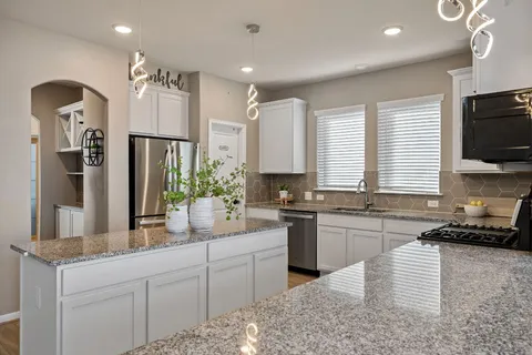a kitchen with kitchen island granite countertop a sink a counter space appliances and cabinets