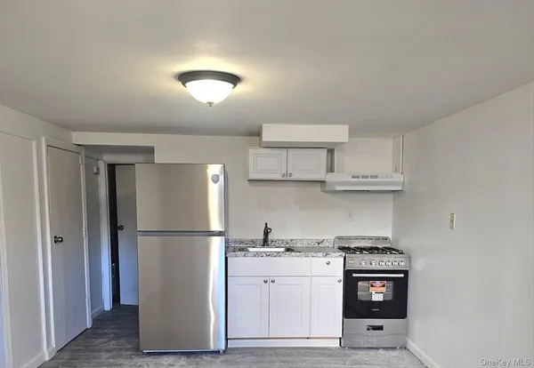 a kitchen with stainless steel appliances granite countertop a refrigerator a sink a stove a microwave and white cabinets