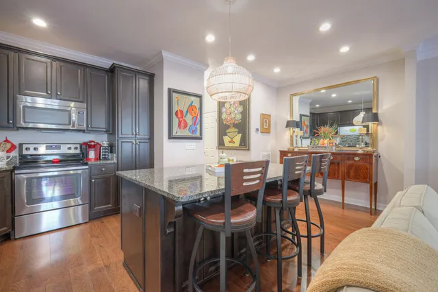 a kitchen with stainless steel appliances kitchen island granite countertop a table chairs and a refrigerator