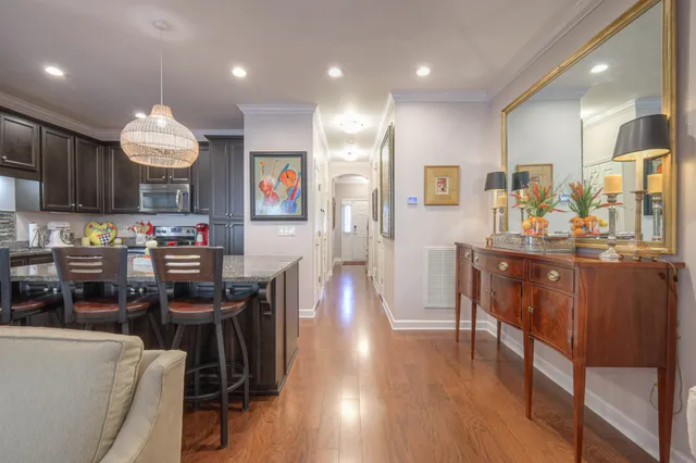 a kitchen with stainless steel appliances granite countertop a refrigerator a stove top oven a sink dishwasher and a dining table with wooden floor