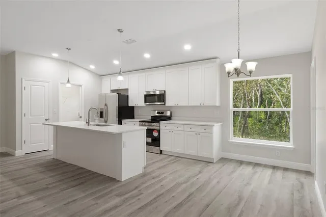 a kitchen with stainless steel appliances granite countertop a stove top oven a refrigerator a sink dishwasher and a fireplace with wooden floor