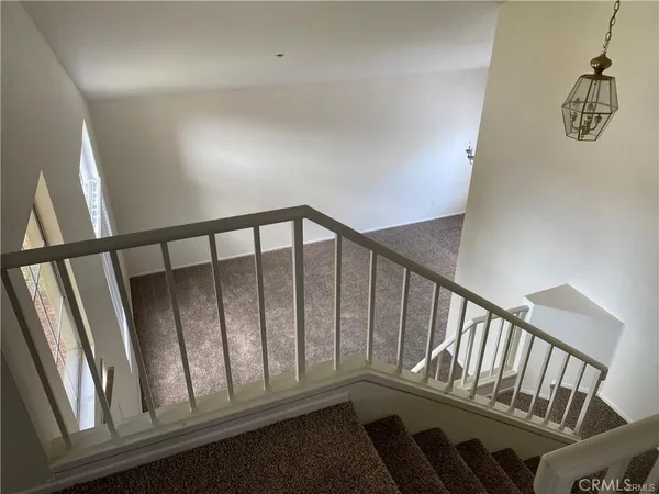 a view of staircase with railing and white walls