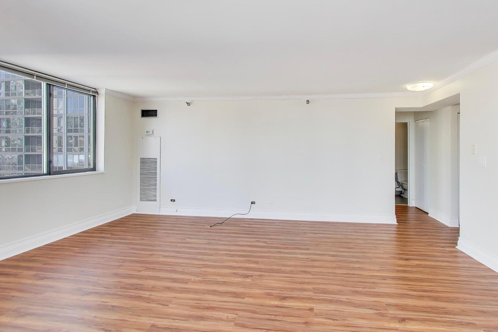 33 West Delaware Place, Unit 12K Chicago, IL 60610 - Photo 9 of 21 a view of an empty room with wooden floor and a window