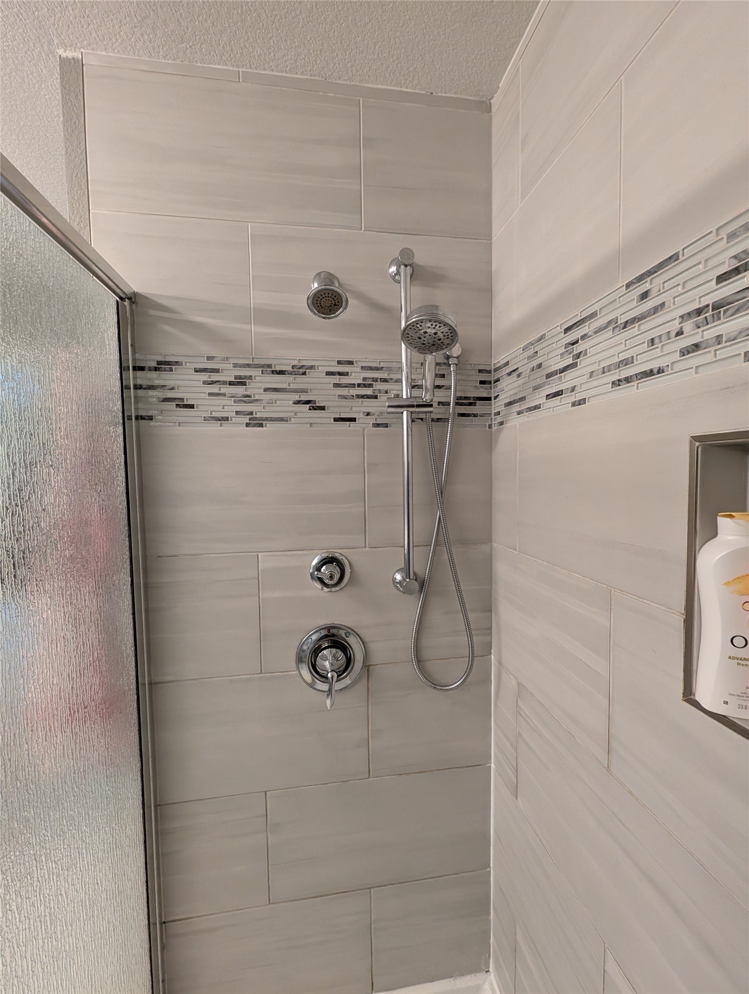 14502 McCoy Loop Austin, TX 78717 - Photo 19 of 26 Shower enclosure featuring light-toned rectangular wall tiles with a horizontal decorative mosaic band