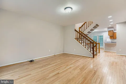 a view of an empty room with wooden floor and stairs
