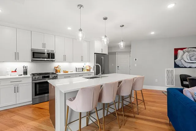 a kitchen with stainless steel appliances kitchen island granite countertop a sink a stove a dining table and chairs