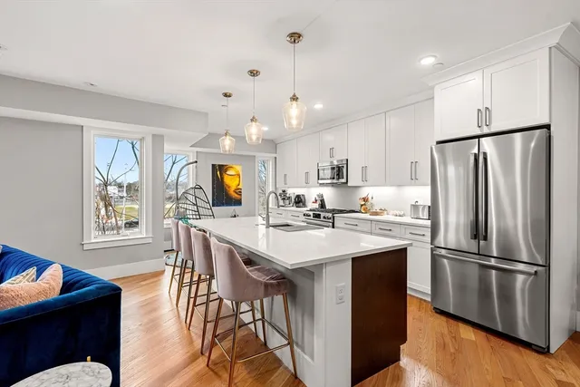 a kitchen with stainless steel appliances a sink a stove a refrigerator cabinets and a dining table