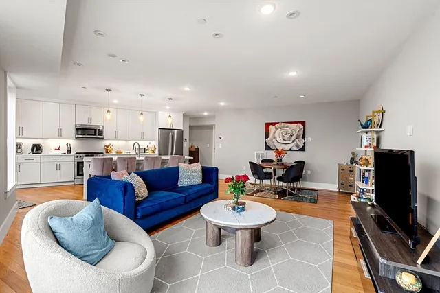 a living room with furniture kitchen view and a flat screen tv