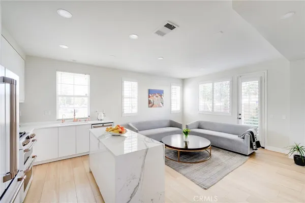 a living room with stainless steel appliances furniture and a wooden floor
