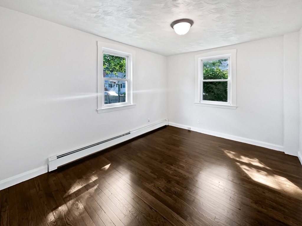 444 Lowell Street Reading, MA 01867 - Photo 19 of 38 a view of an empty room with wooden floor and a window