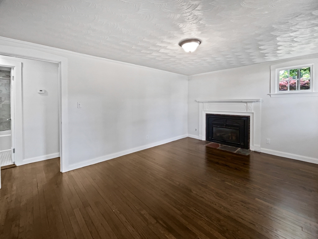 444 Lowell Street Reading, MA 01867 - Photo 22 of 38 an empty room with wooden floor and fireplace
