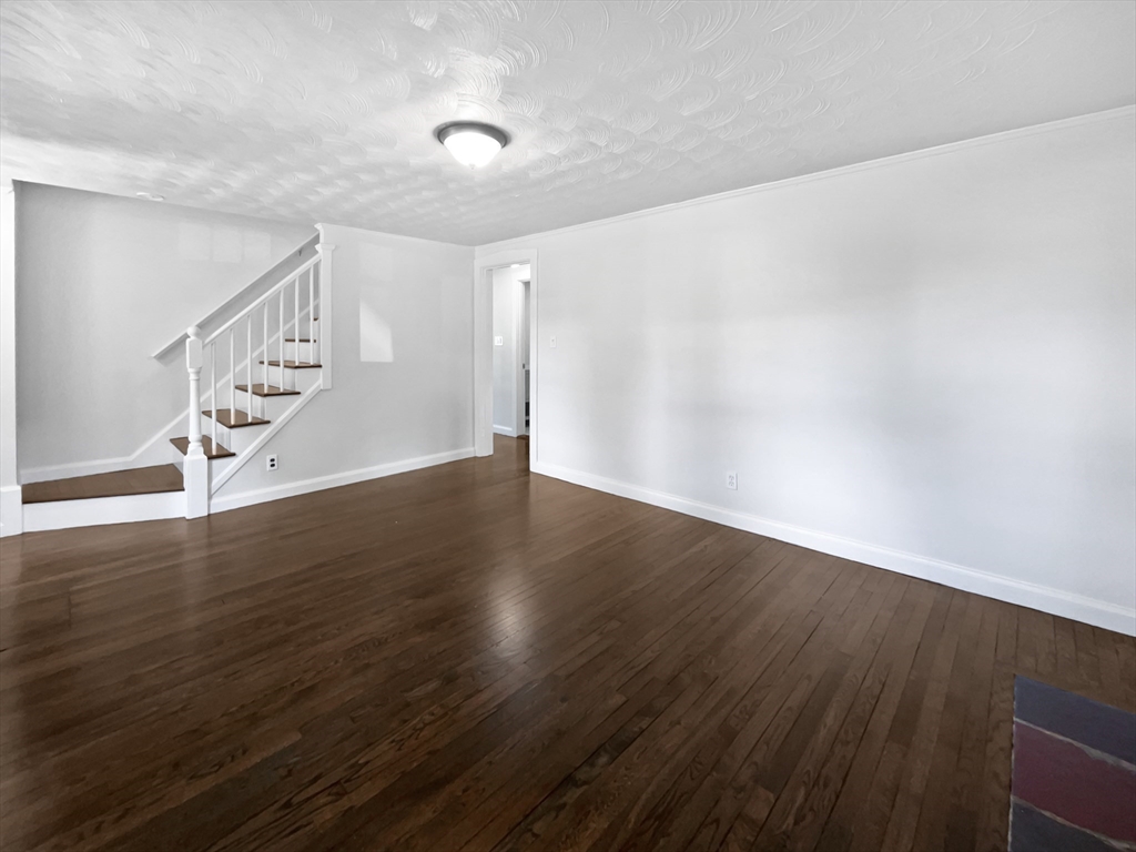 444 Lowell Street Reading, MA 01867 - Photo 29 of 38 a view of an empty room with wooden floor and stairs