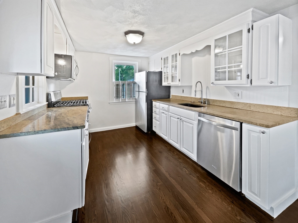 444 Lowell Street Reading, MA 01867 - Photo 6 of 38 a kitchen with granite countertop a sink stove and cabinets