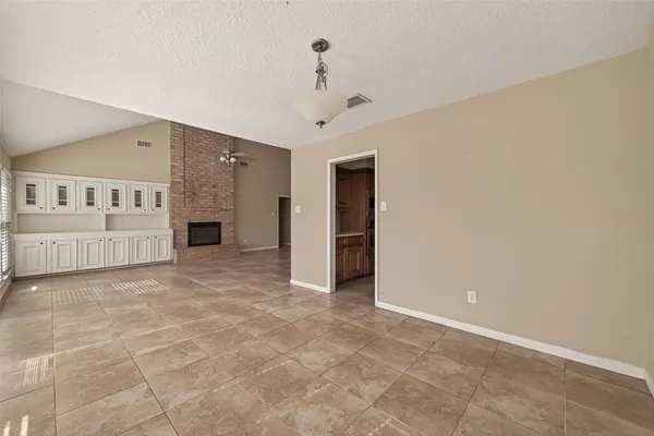 a view of an empty room with wooden floor and a ceiling fan