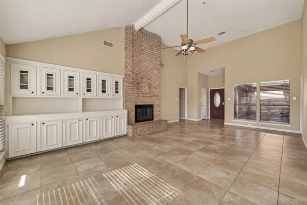 an empty room with wooden floor fan and windows