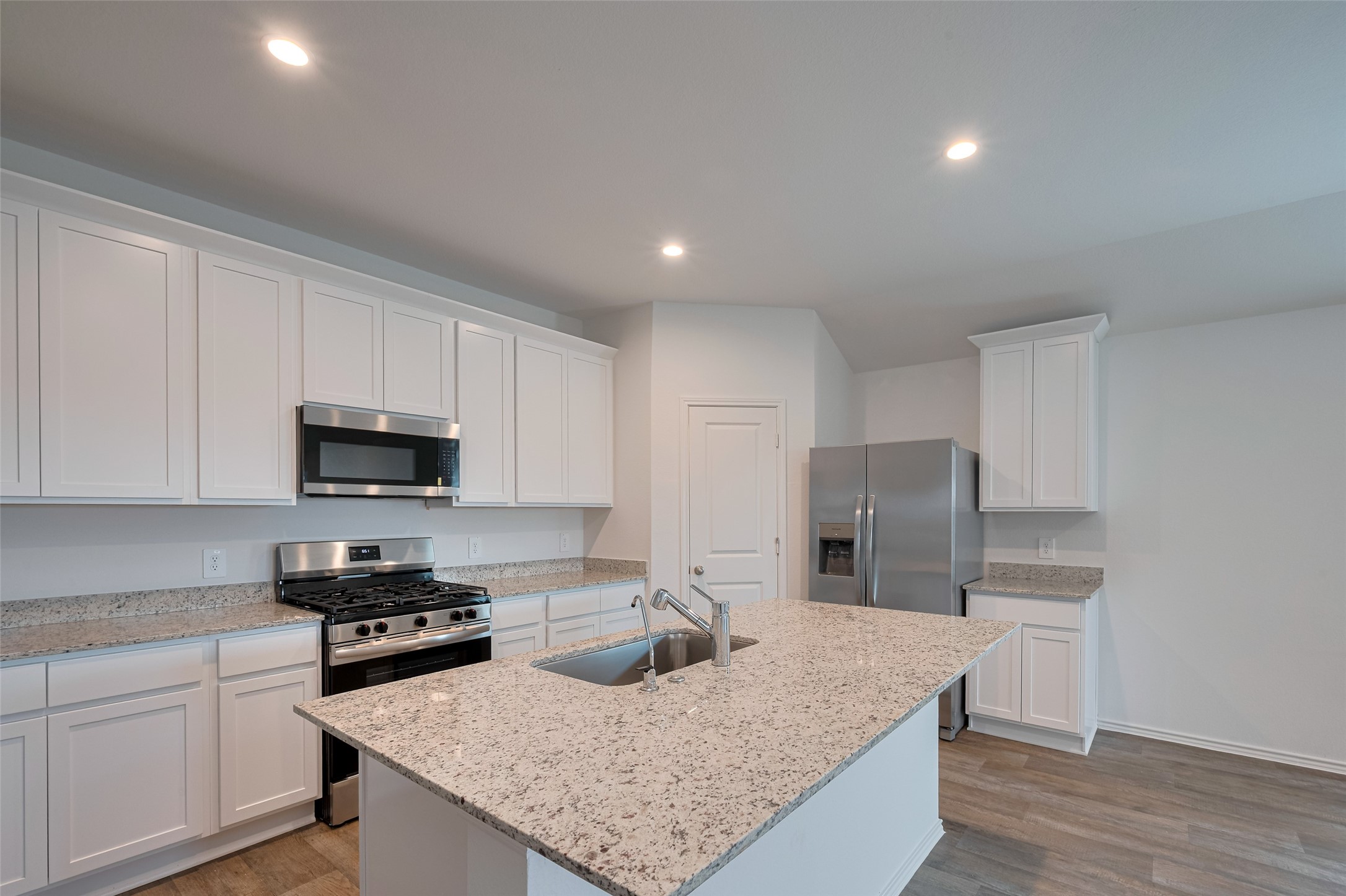 30910 Rockstock Road Fulshear, TX 77441 - Photo 4 of 33 Sleek white cabinetry above and below provides ample storage, while generous countertops offer space to prep, serve, and enjoy. The clean design enhances the kitchen’s streamlined appeal.