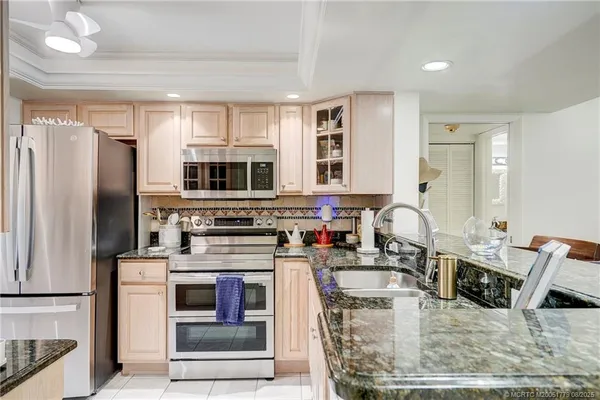 a kitchen with stainless steel appliances granite countertop a stove top oven a sink and a refrigerator