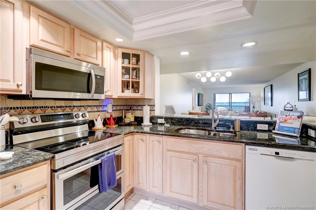 10 Northeast Plantation Road, Unit 101 Stuart, FL 34996 - Photo 10 of 36 a kitchen with stainless steel appliances granite countertop a stove microwave and cabinets