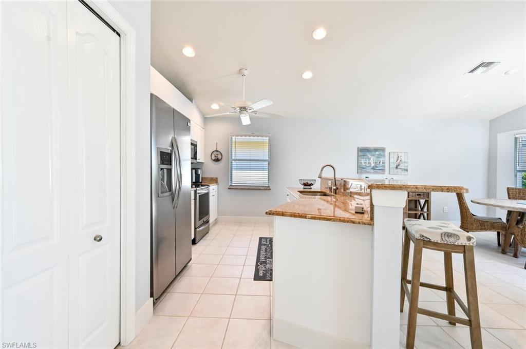 8449 Indian Wells Way Naples, FL 34113 - Photo 11 of 35 a kitchen with stainless steel appliances kitchen island granite countertop a refrigerator and a sink