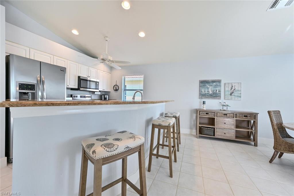 8449 Indian Wells Way Naples, FL 34113 - Photo 12 of 35 a kitchen with stainless steel appliances a stove a table and chairs