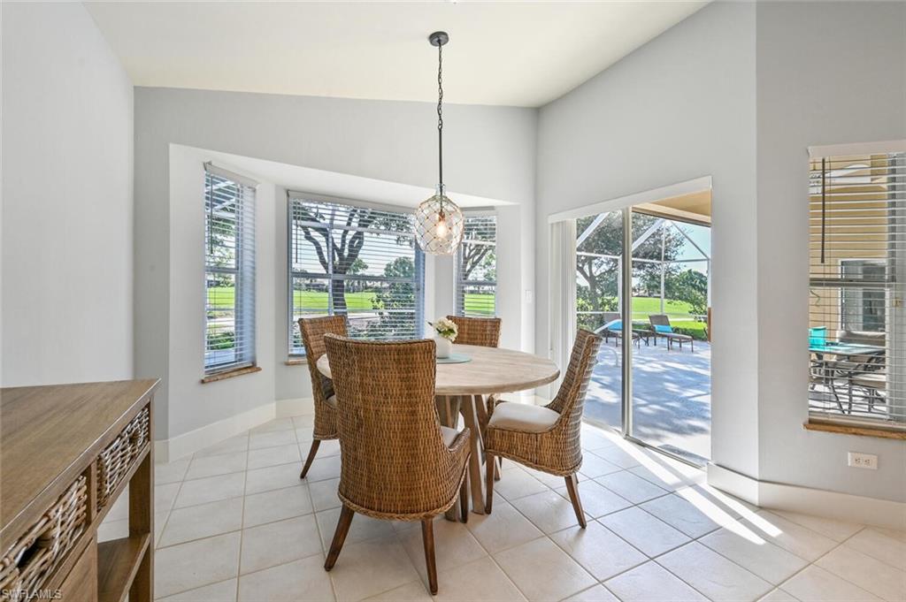 8449 Indian Wells Way Naples, FL 34113 - Photo 9 of 35 a dining room with furniture large windows and a chandelier