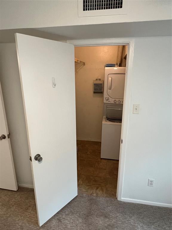3929 Inwood Road, Unit 2021 Dallas, TX 75209 - Photo 18 of 24 Laundry area featuring a stacked washer and dryer, patterned flooring, and an overhead storage shelf