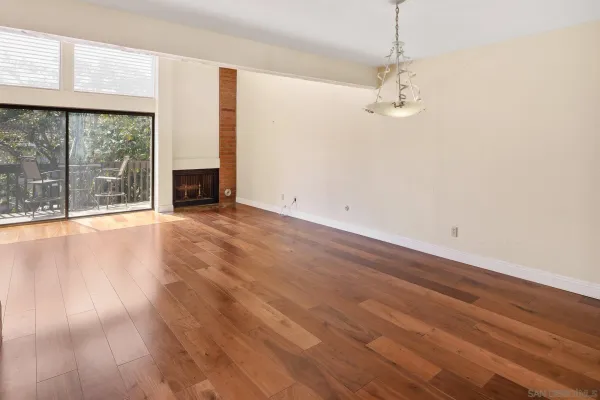 an empty room with wooden floor fireplace and windows
