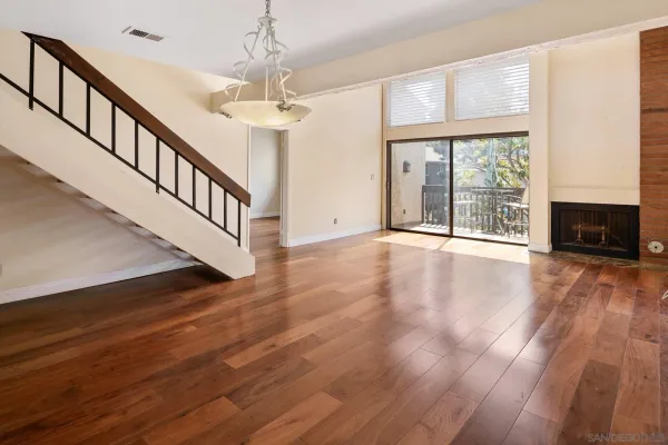 a view of an empty room with wooden floor fireplace and a window