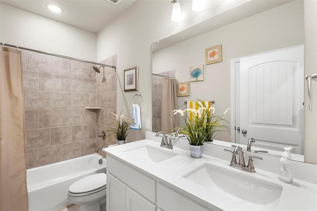107 Yampa Court Rhome, TX 76078 - Photo 17 of 30 Bathroom featuring a dual vanity with white cabinetry and integrated sinks, a full-width mirror, and overhead lighting