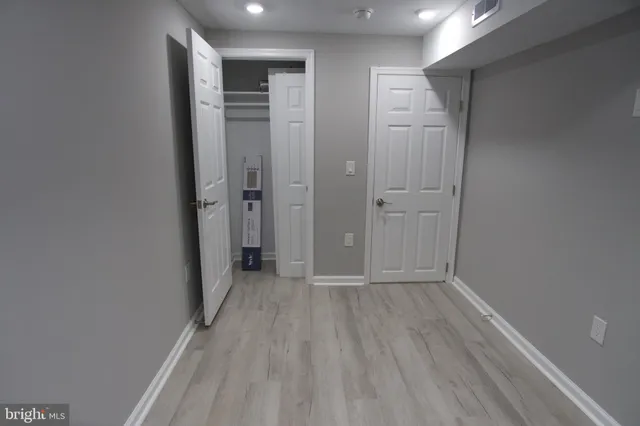 a view of an empty room with wooden floor and closet area