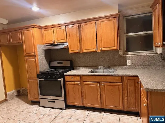 a kitchen with stainless steel appliances granite countertop a stove a sink and a refrigerator with wooden cabinets