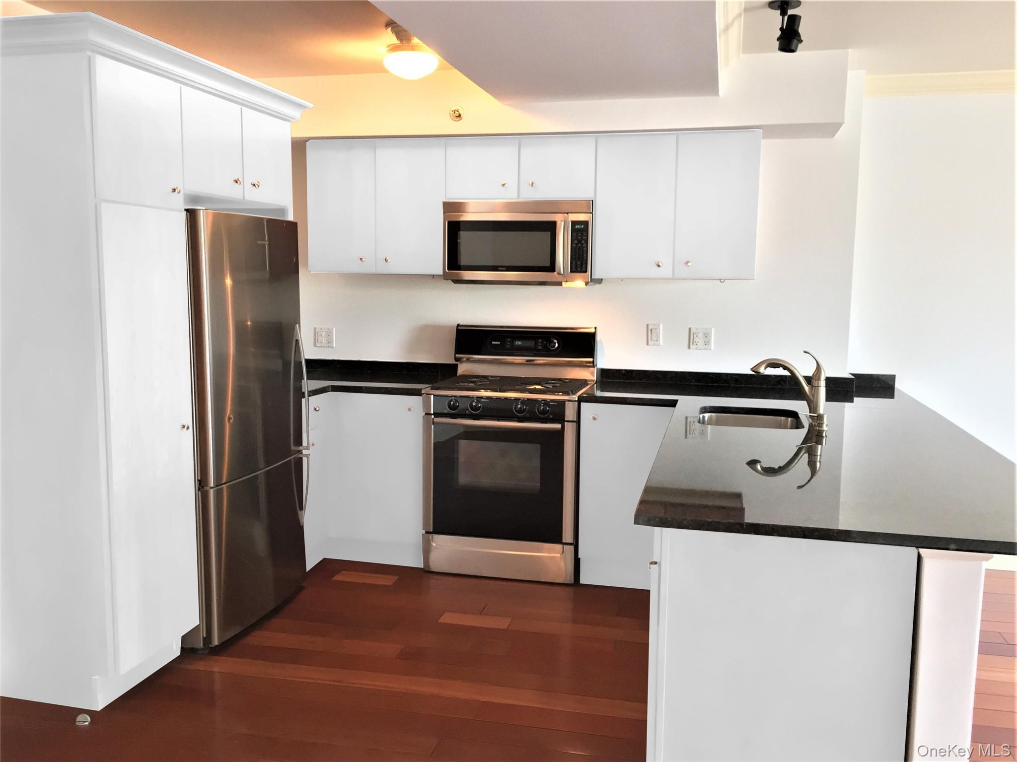 1 South Astor Street, Unit 202 Irvington, NY 10533 - Photo 5 of 13 Kitchen with a peninsula, dark wood-style floors, white cabinets, stainless steel appliances, and a sink