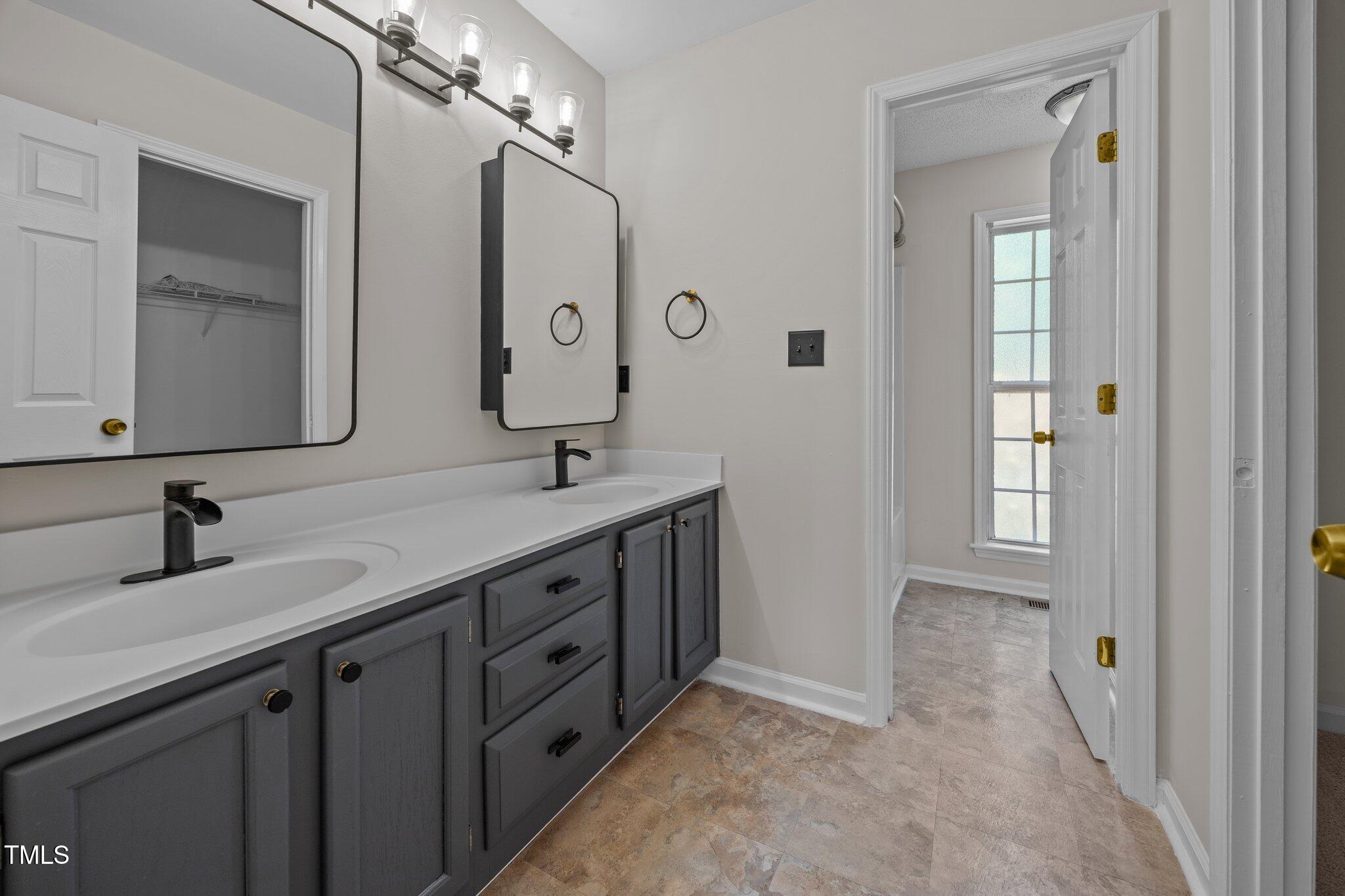 408 Flagg Road Holly Springs, NC 27540 - Photo 18 of 32 a bathroom with a double vanity sink and a mirror