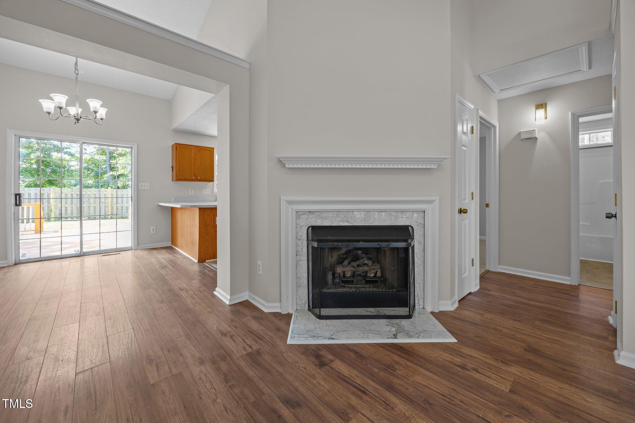 408 Flagg Road Holly Springs, NC 27540 - Photo 5 of 32 a view of an empty room with wooden floor a fireplace and a window